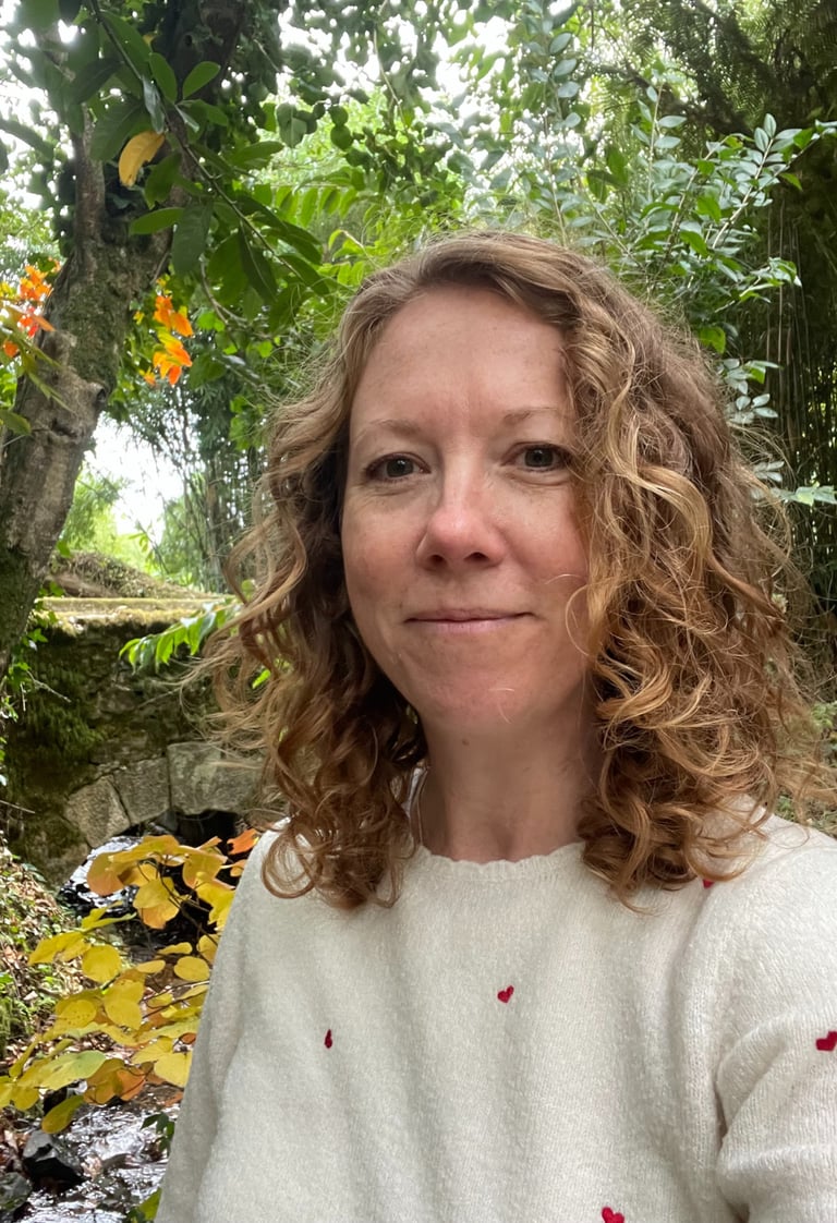 Headshot of Iona Reading standing in front of trees and a bridge