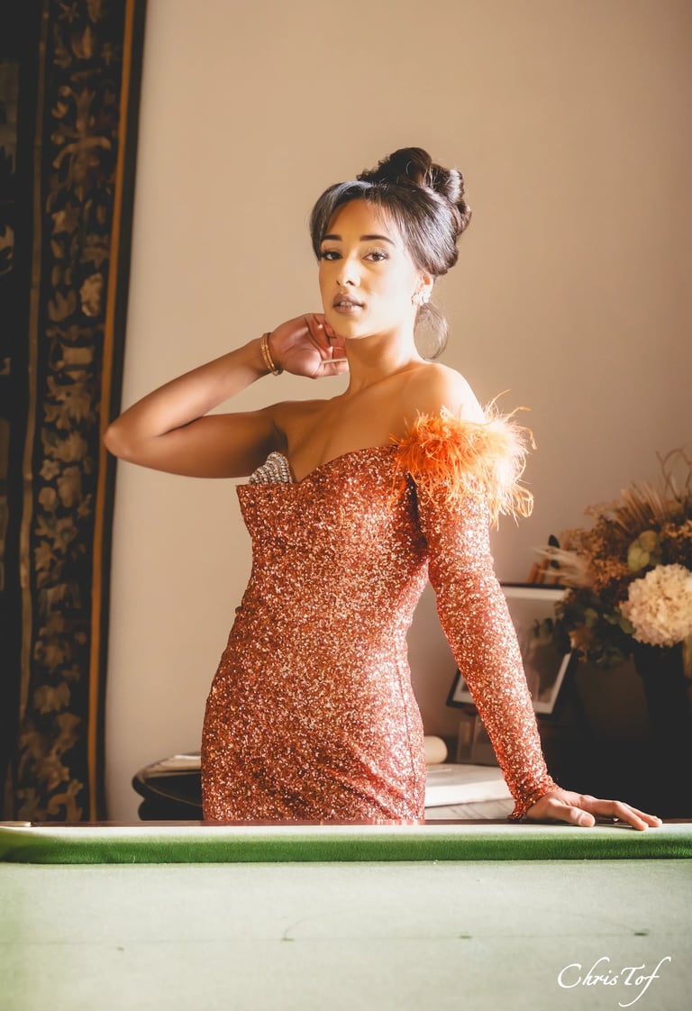 Portrait d'une femme en robe de soirée et plumes, posant près d'un billard au chateau de valmy 66.
