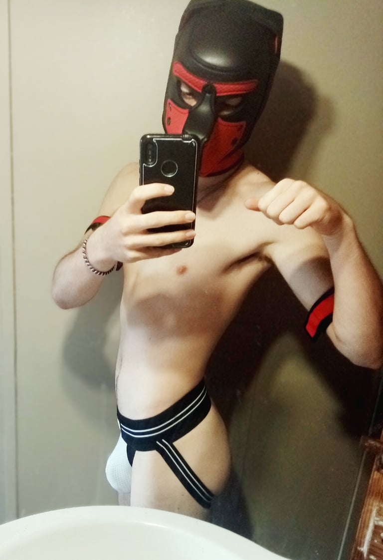 A Man posing for a selfie in a jock and pup mask.