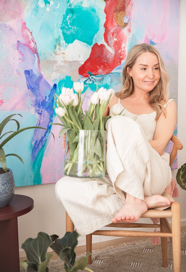 the therapist Saija Uussaari sitting in a chair with a vase of flowers