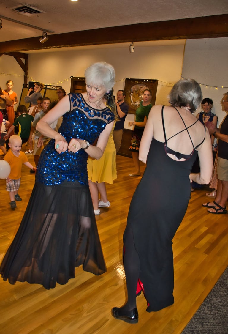 a woman in a blue dress dancing with a woman in a black dress