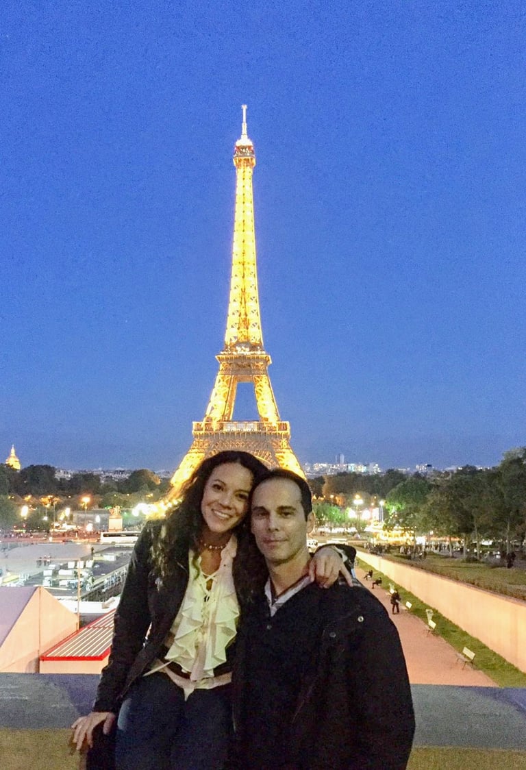 Couple standing in front of illuminated Eiffel Tower at night in Paris France