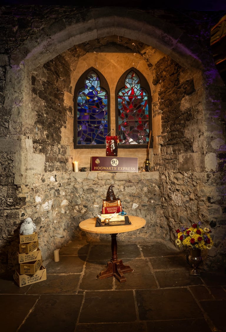 Harry Potter–themed birthday cake table by stone wall and stained glass, Fred Art Studio.