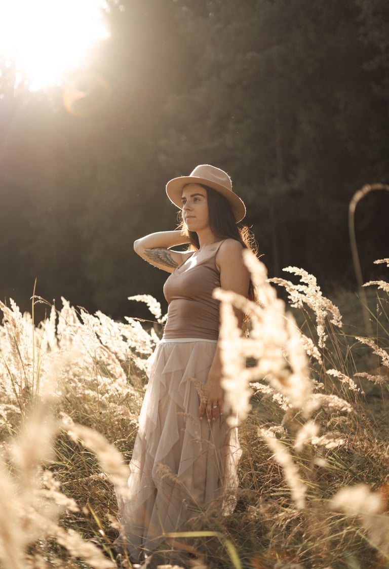 woman standing in long grass during sunset
