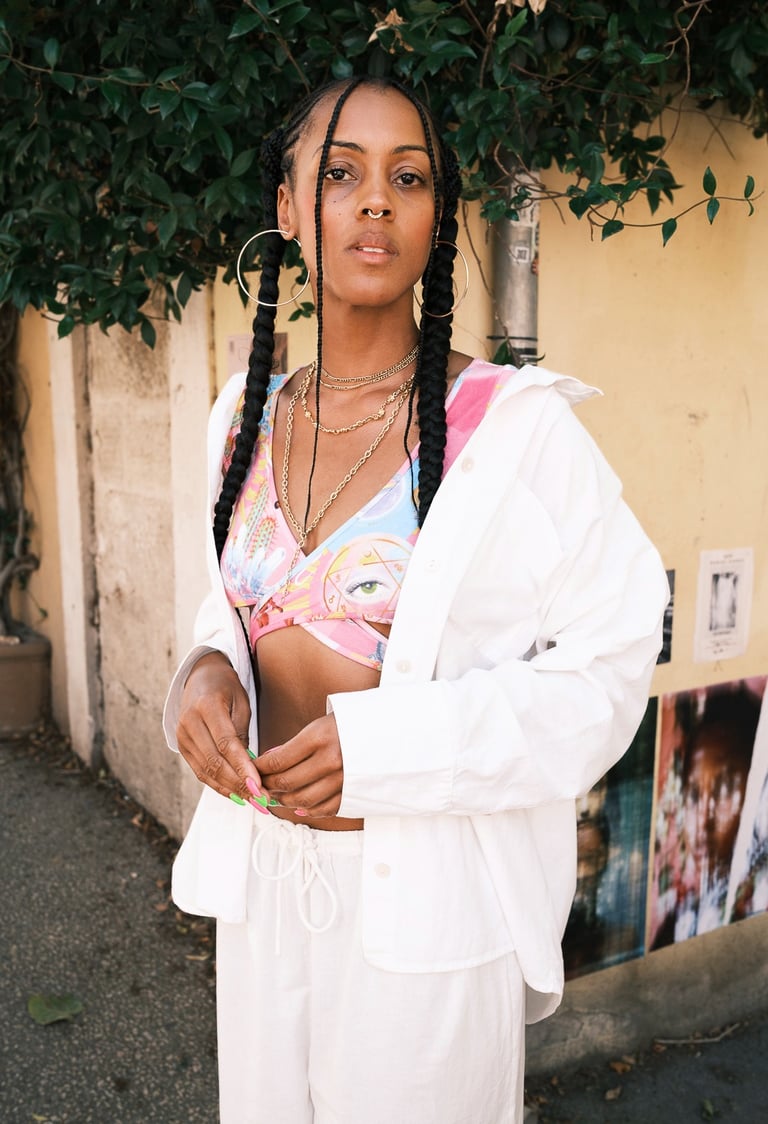 portrait d'une femme noire avec brassière colorée et pantalon ample blanc