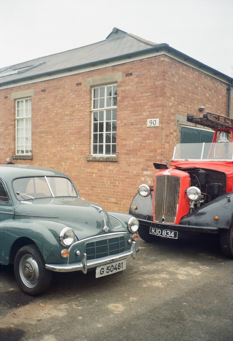two classic cars parked in front of a brick building