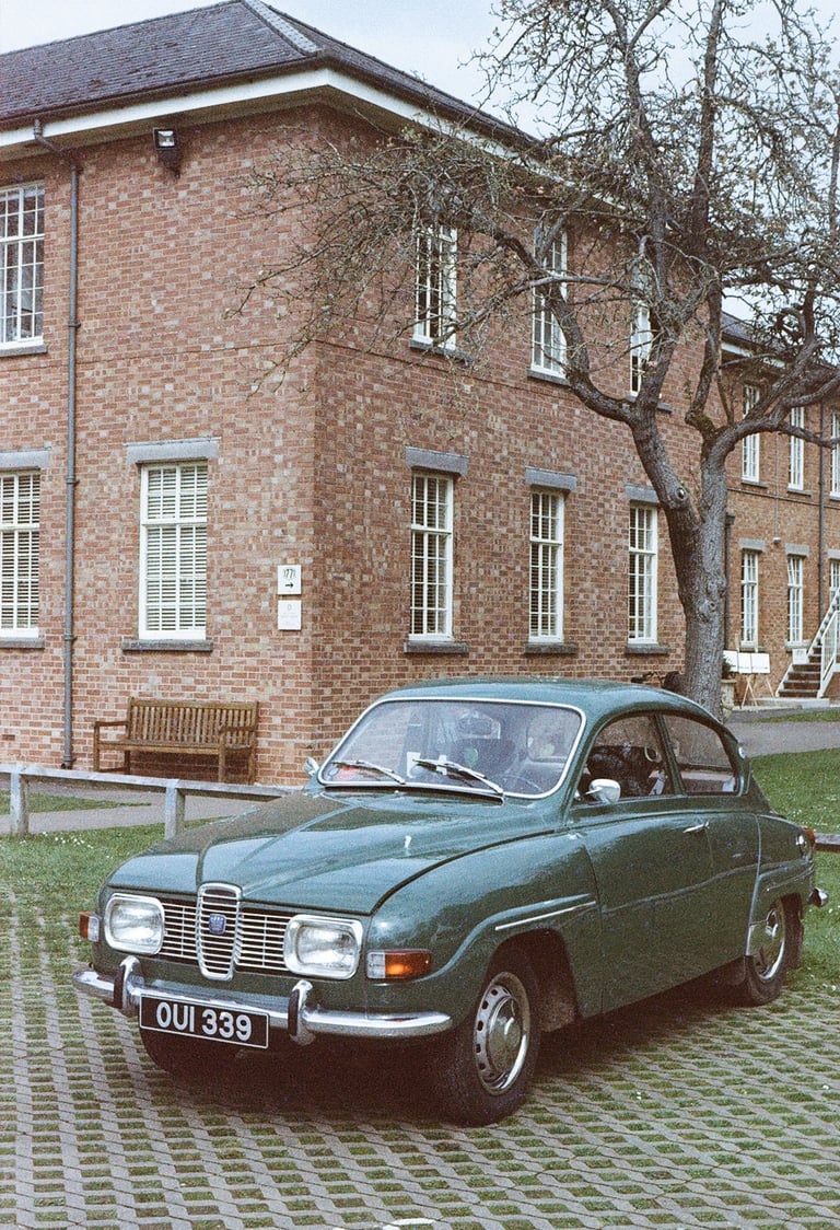 a green classic car parked in front of a brick building
