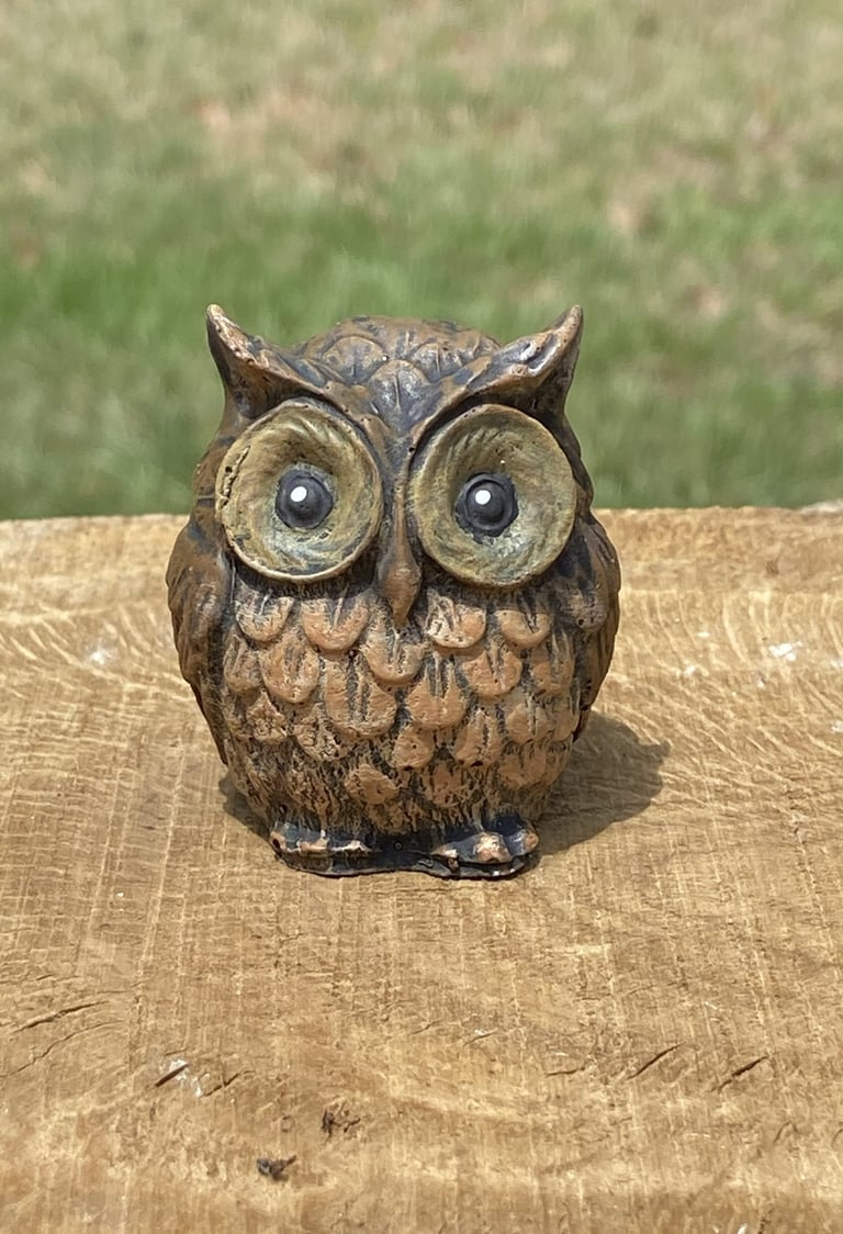 Small brown decorative concrete owl figurine.