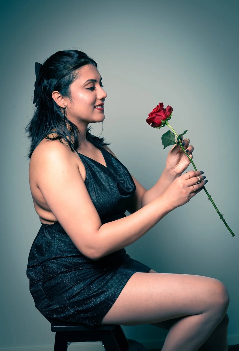 a woman in a black dress sitting on a stool