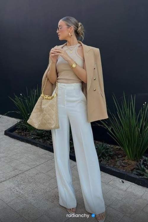 a woman in a beige coat and white pants