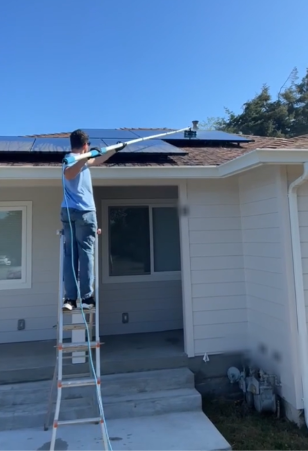 Cleaner from Chez Cleaning Services washing solar panels with a water fed pole and brush