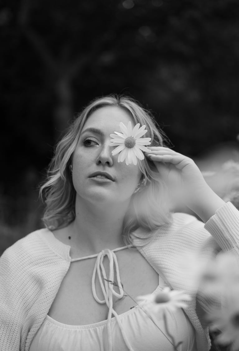 black and white image woman holding flower infront of her face