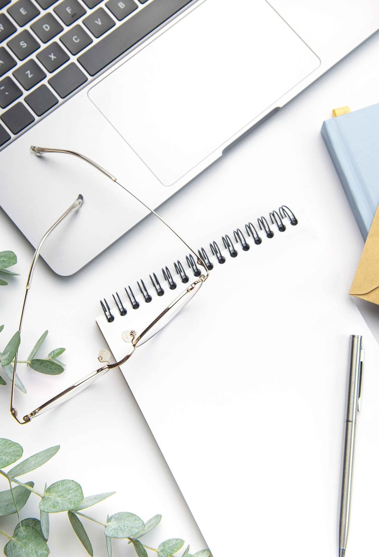 Image of a notebook with a laptop, glasses and eucalyptus leaves