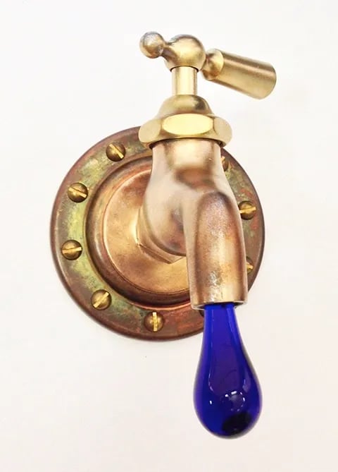 Vintage brass faucet with dark blue glass drip coming out ot the spout.