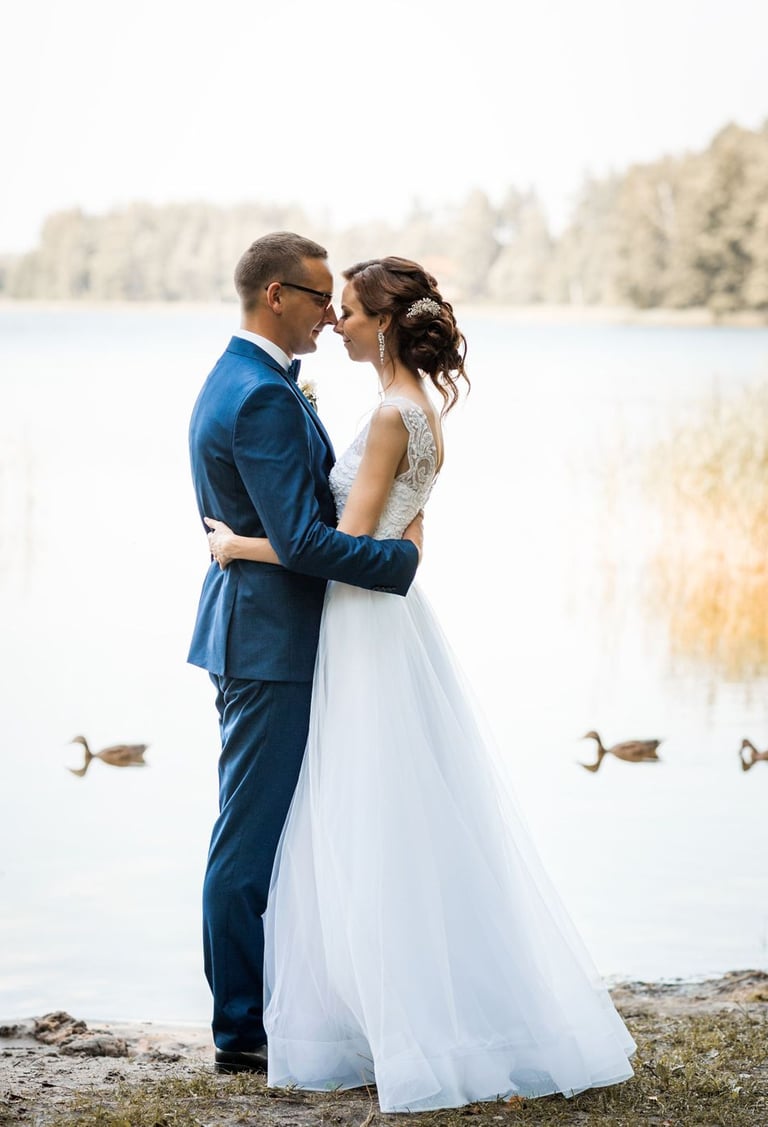a bride and groom standing in front of a lake