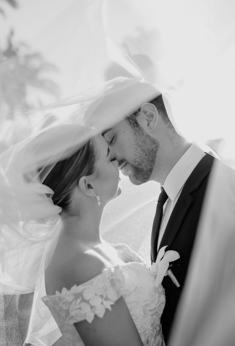 a bride and groom kissing in a veiled veil