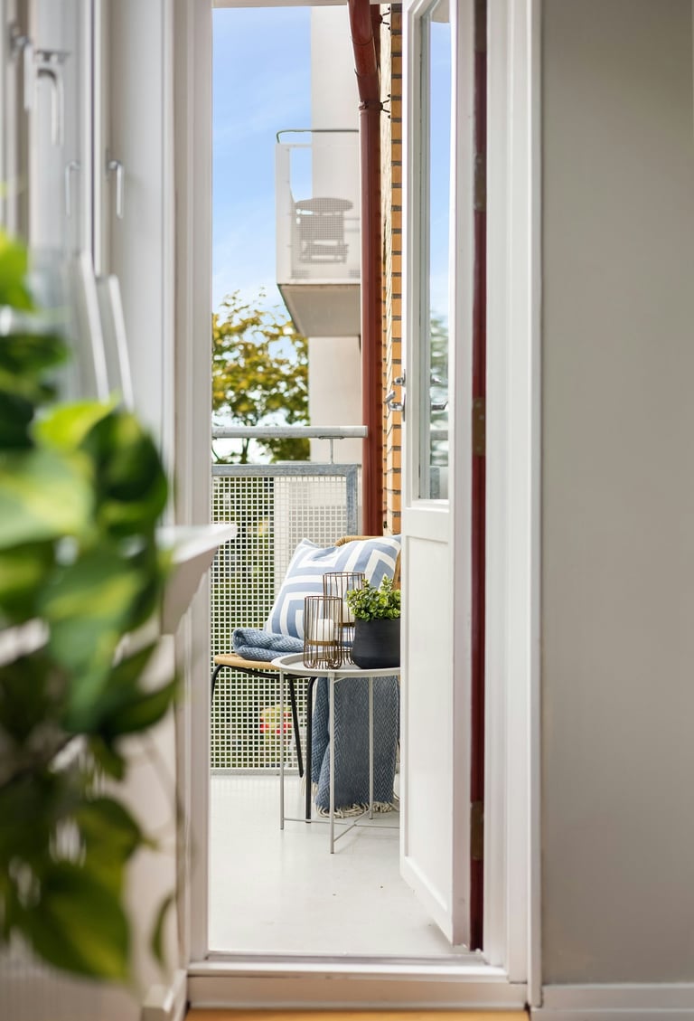 Balcony doorway with outdoor seating and city view in a bright apartment