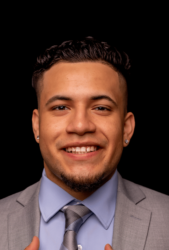 Photo of Isaac in grey suit and blue undershirt with a grey and blue tie.