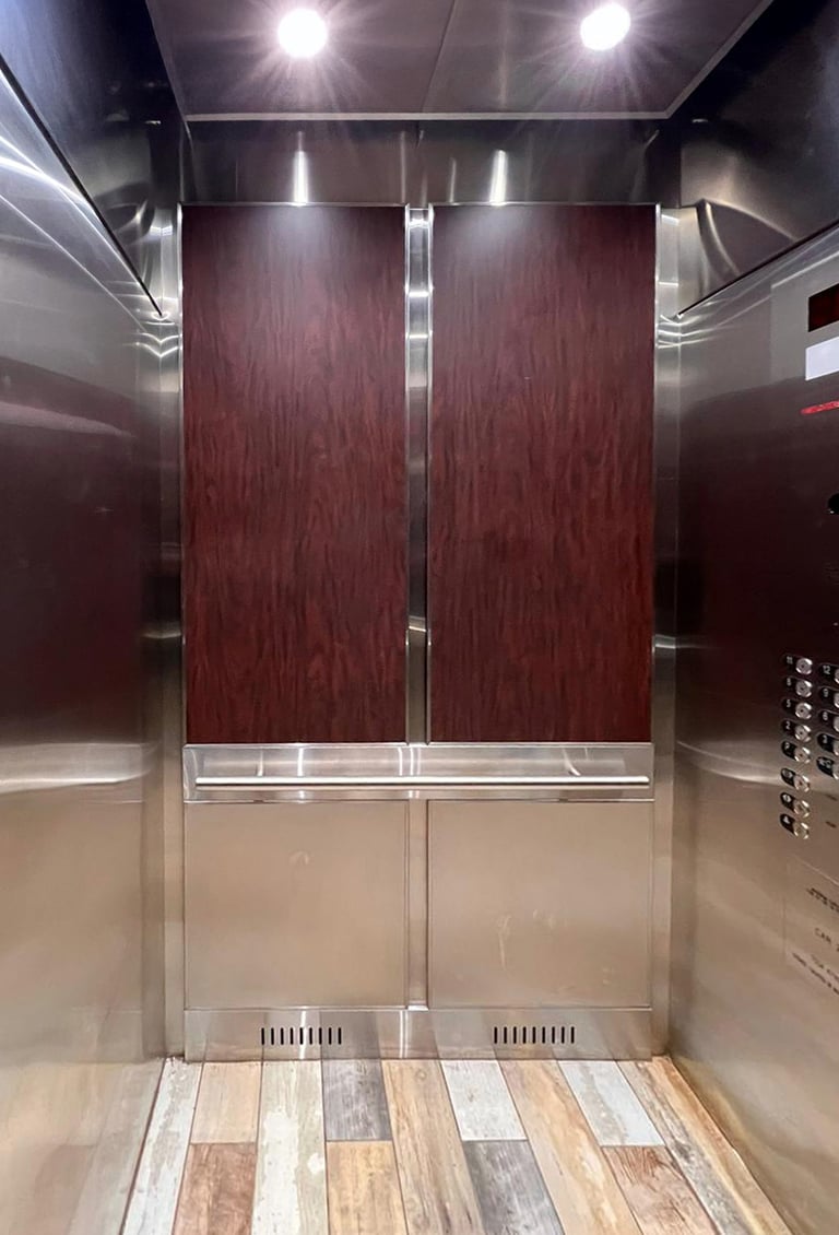 elevator interior with deep red wood wall panels, round handrails and a warm tile floor