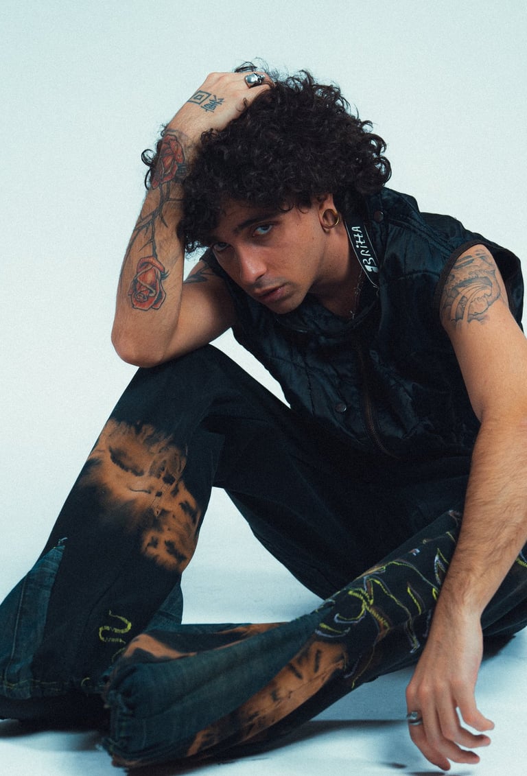 Klaus Noir su sfondo bianco seduto e con una mano in testa