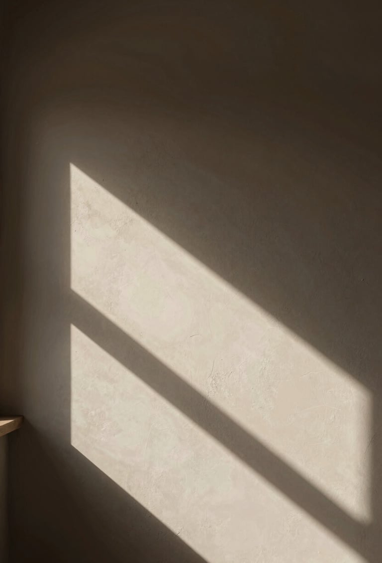 A contemplative scene in a South American / Argentine art studio. Soft afternoon light filtering through a window, casting long deep charcoal shadows on a textured soft off-white wall. Muted earthy brown tones dominate the composition.