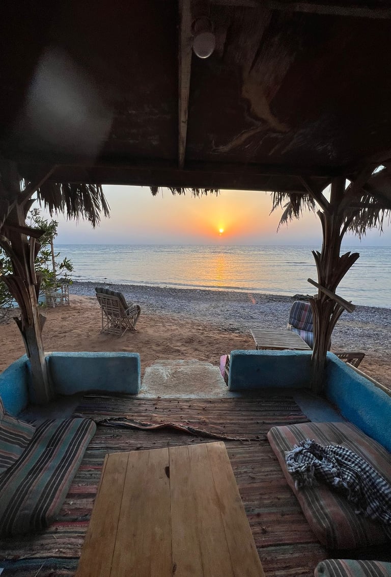 Een terras van een populaire strandkamer met een bank met tafel en stoelen tegenover een strand
