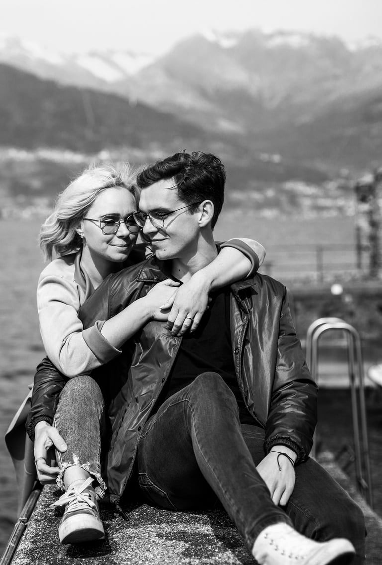 a man and woman sitting on a ledge overlooking the water