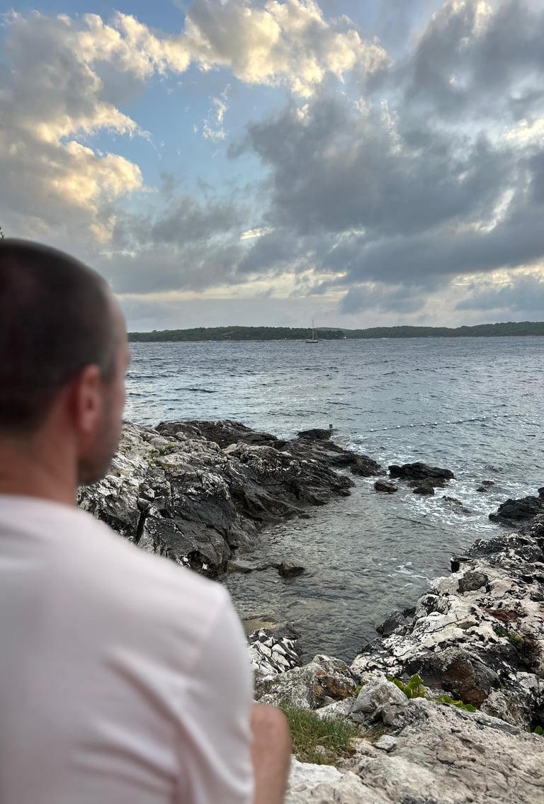 a man in white t shirt looks out to sea