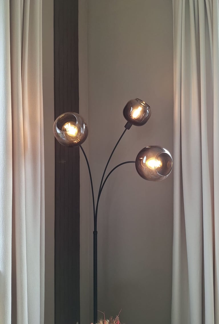 Zoom sur un luminaire sur pied avec trois globes lumineux en verre