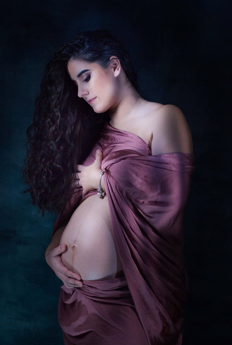 Femme enceinte drapé d'un voile pourpre antique caressant son ventre rond et baissant son regard