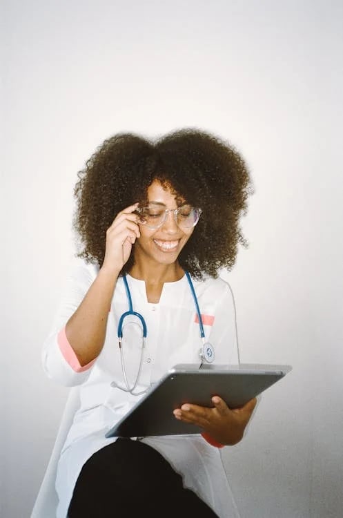 a woman in a white lab coat and glasses talking on a cell phone