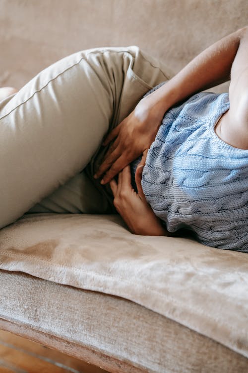 a woman laying on a couch with her hands on her stomach