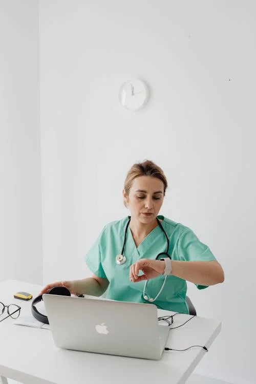 a nurse in scrubs and a stethoscope on a laptop