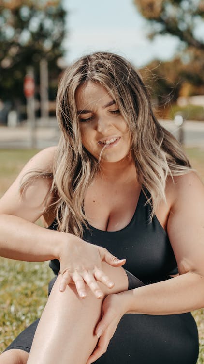 a woman in a black swimsuit sitting on a bench in the grass