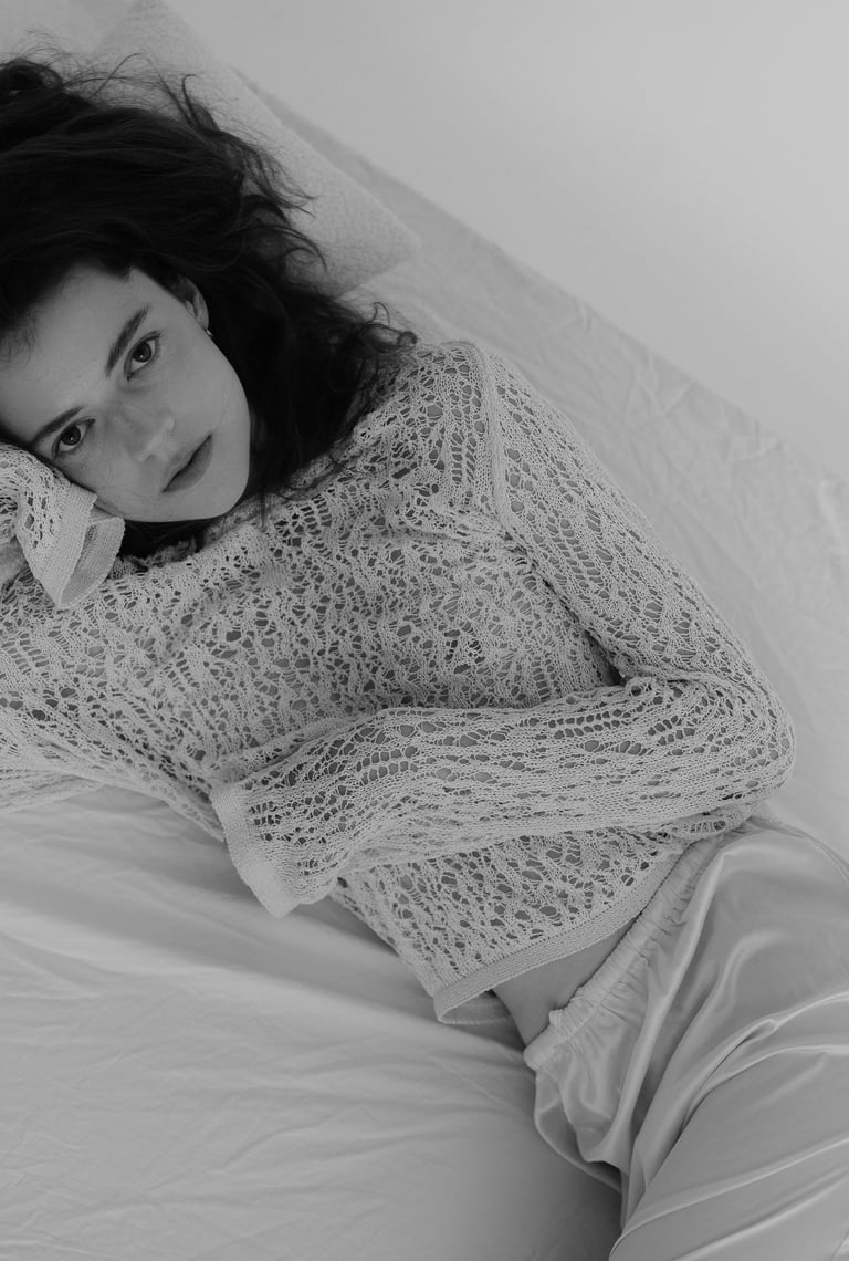 a woman laying on a bed with her hand on her head