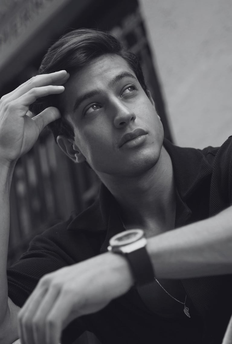 Black and white photo of man taking posed selfie in smart attire, modeling-style expression