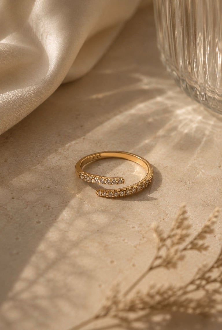 Gold crystal open ring with sparkling stones styled on a neutral stone surface.