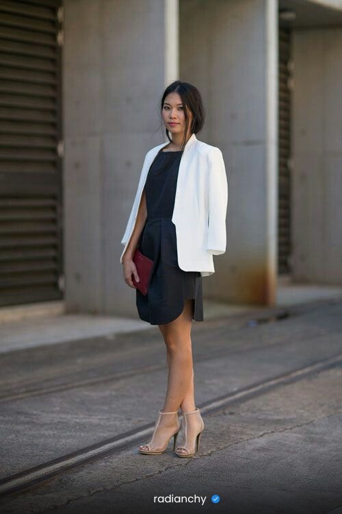a woman in a black dress and white jacket