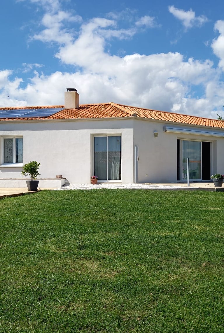 une grande maison blanche avec deux baies vitrées et une fenêtre