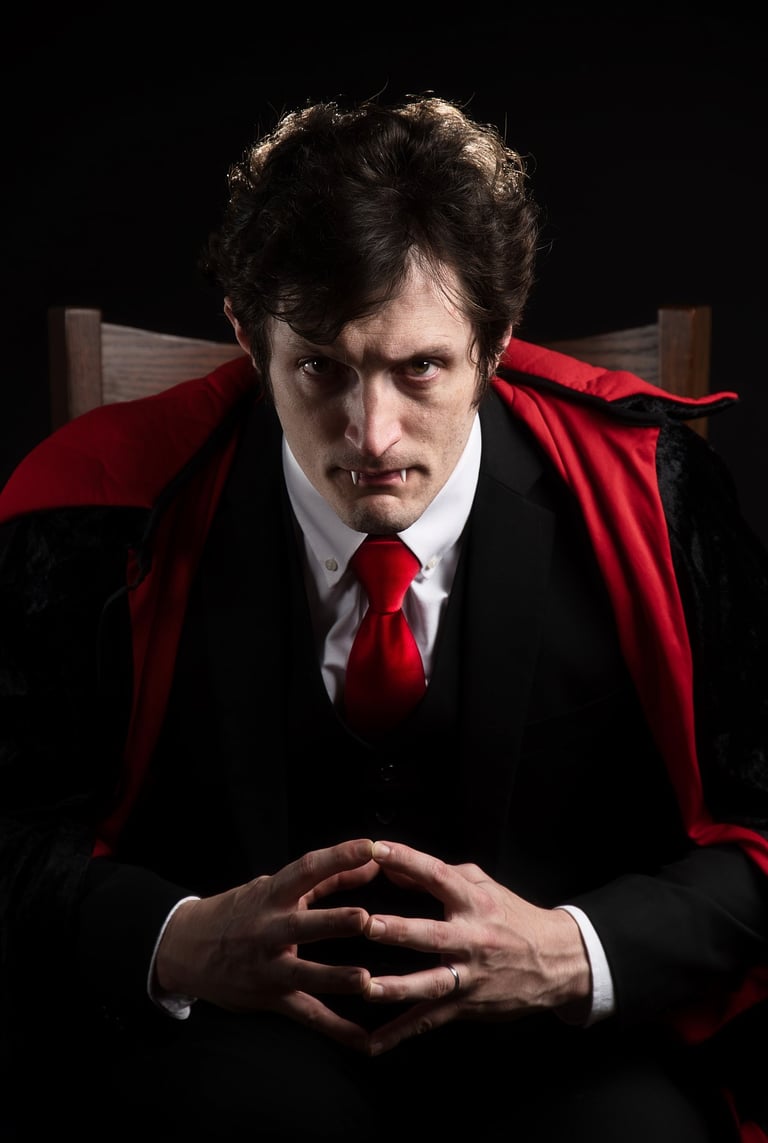 a man in a vampire suit with vampire teeth out and tie with a red tie  