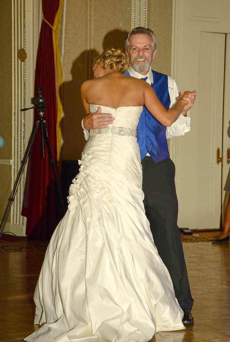 a bride and her father dancing at a wedding in a hotel ball room