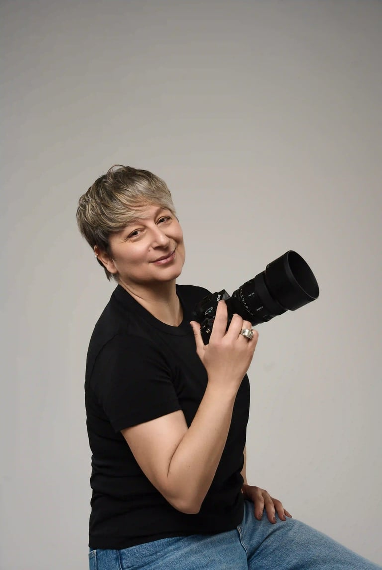 Tania Dina, fotógrafa profesional sosteniendo su cámara con una sonrisa auténtica