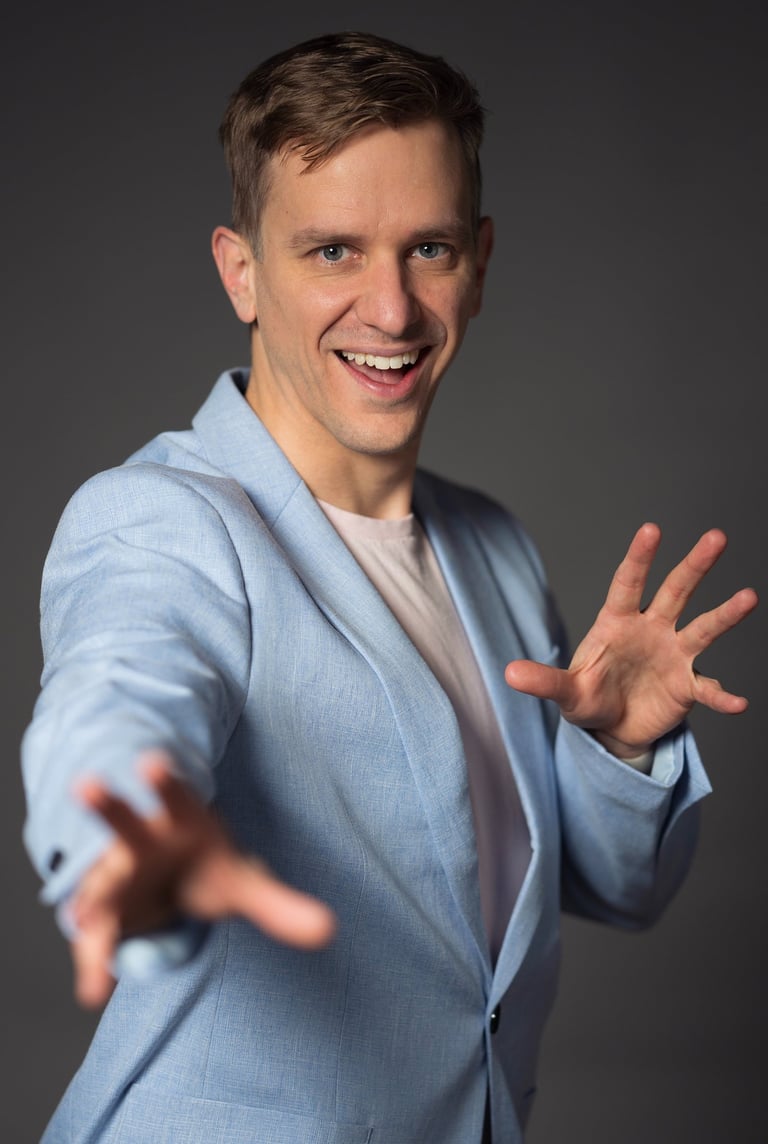Remy wearing a blue blazer and smiling, hands open to the viewer