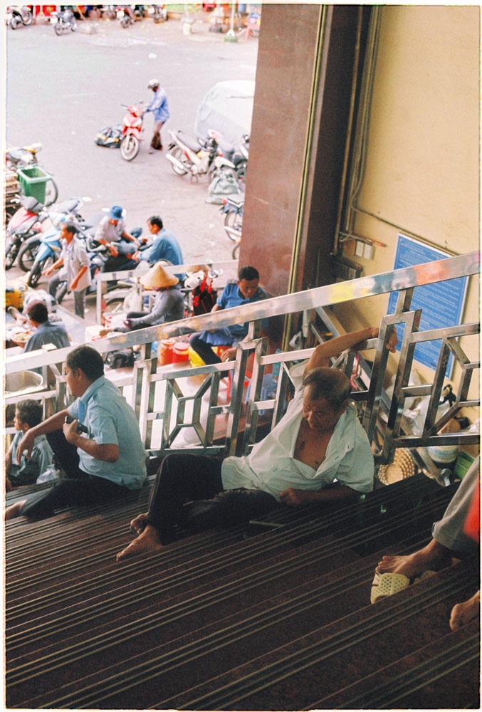 Vietnamese vendor relaxing on the stairs in Saigon China town market