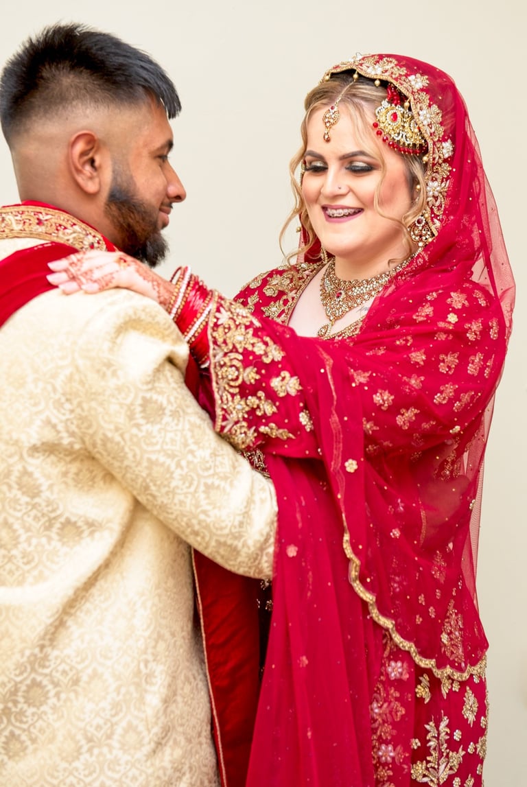 candid photo of bride and asian groom, bride's hand on groom shoulder, both laughing and having a good time