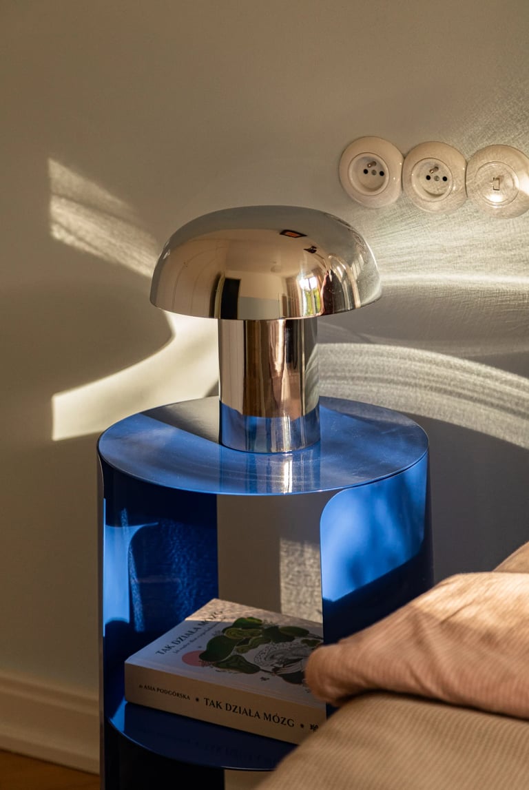 Gra światła w fotografii: chromowana lampa i niebieski stolik.
