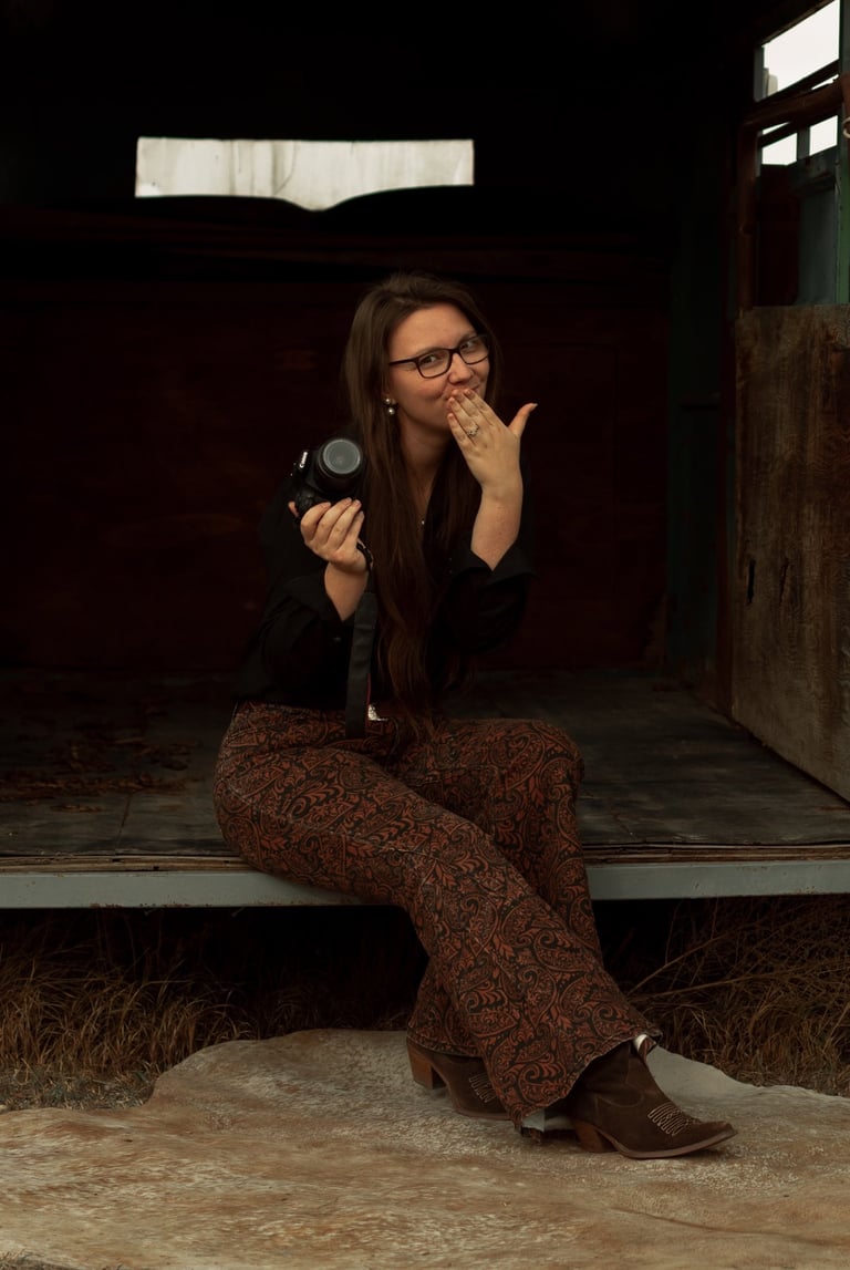 a woman is sitting, holding a camera