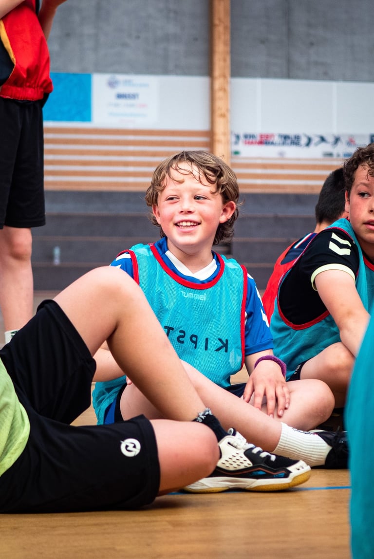 a group of young boys sitting on a basketball court