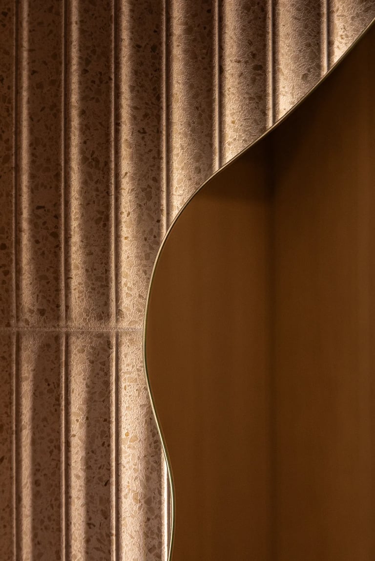 Detal faktury: ryflowane płytki, nieregularne lustro i oświetlenie.