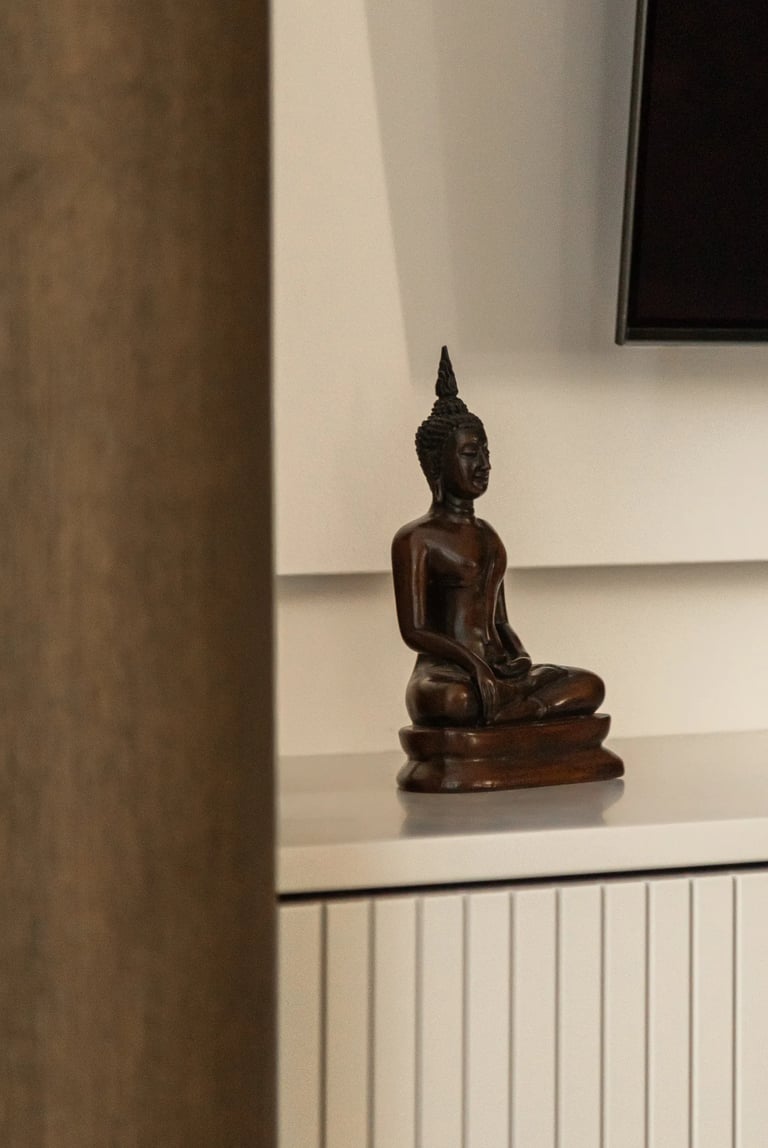 Zbliżenie na dekoracje: drewniana figurka Buddy w minimalistycznym wnętrzu.